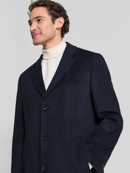 Männermodel trägt Mantel mit Reverskragen und Eingrifftaschen von bugatti in Dunkelblau, glatte Textur, Nahaufnahme Oberkörper, Regular Fit, Knopfleiste, Kontext: Rückenlänge 99 cm, Schulterbreite 45 cm, Brustweite 57 cm, Ärmellänge 66 cm.