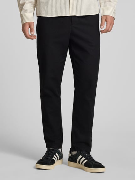 Männermodel trägt Tapered Leinenhose aus Baumwoll-Leinen-Mix Modell 'LINUS' von Only & Sons in zwart melange met elastische tailleband en steekzakken, vooraanzicht, Ganzkörperansicht von vorne.