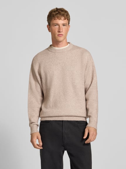 Männermodel trägt Strickpullover mit Rundhalsausschnitt Modell 'SOHO OLLIE' von JACK & JONES, beige, Struktur mit Woll-Anteil, Ganzkörperansicht von vorne.