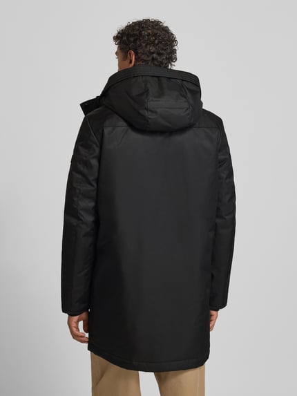 Männermodel trägt Jacke mit Pattentaschen Modell von NAUTGÅRD in Schwarz, Regular Fit, Kapuze, Rückenlänge 96 cm, Ganzkörperansicht Rückansicht.