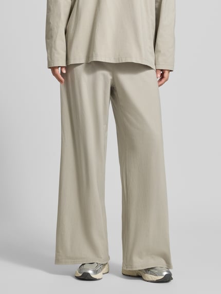 Frauenmodel trägt Wide Fit Hose aus reiner Baumwolle Modell 'GIXY' von American Vintage in Beige, elastischer Bund, Ganzkörperansicht von vorne.