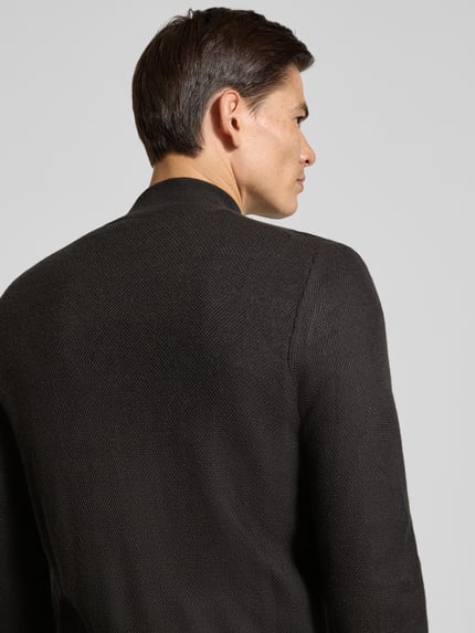 Männermodel trägt Strickjacke aus Wolle mit Stehkragen von JOOP! in dunkler Unifarbe, Strickoptik, Nahaufnahme Oberkörper, Rückansicht.