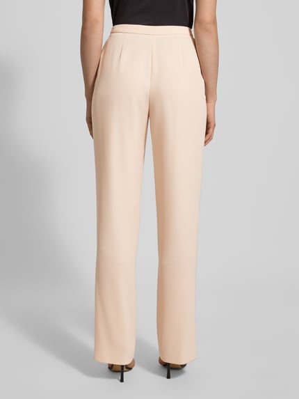 Frauenmodel trägt Stoffhose mit Bundfalten von Emporio Armani in Beige, lockerer Schnitt, Bundfalten, Ganzkörperansicht Rückansicht.