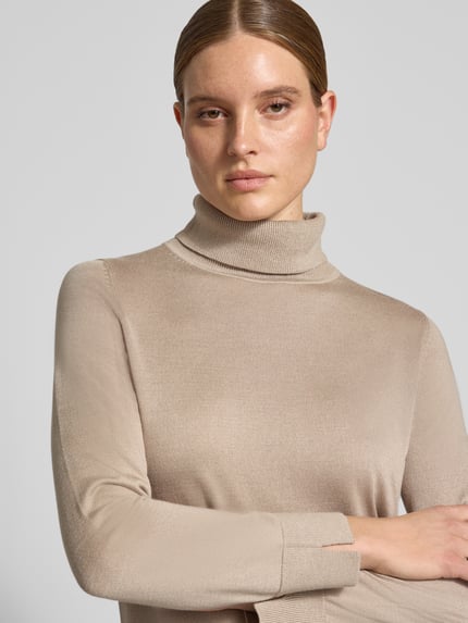 Frauenmodel trägt Regular Fit Pullover aus Viskose-Mix von COMMA in Beige, Rollkragen, glatte Strick-Optik, Nahaufnahme Oberkörper.