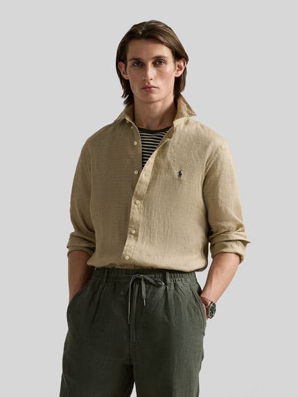 Männermodel trägt Slim Fit Freizeithemd aus reinem Leinen von Polo Ralph Lauren in Beige, unifarben, mit Logo-Stitching, Ganzkörperansicht von vorne.