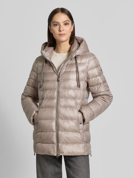 Vrouwenmodel draagt Regular Fit Mantel in stiksels van FUCHS SCHMITT in beige met capuchon, tunnelkoord, opstaande kraag, steekzakken, tweewegritssluiting; ruglengte maat 36: 76 cm, schouderbreedte: 46 cm, borstwijdte: 50 cm, mouwlengte: 66 cm. Ganzlichaansicht van voren.