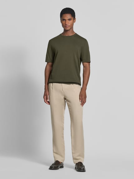 Männermodel trägt Regular Fit T-Shirt aus reiner Baumwolle Modell 'TORINO' von SELECTED HOMME, unifarbenes Olivgrün, Rundhals, kurzarm, gerippte Abschlüsse, Ganzkörperansicht von vorne.
