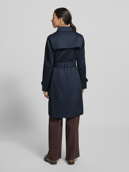 Vrouwenmodel draagt 'Mantel mit Stoffgürtel' van Jake*s Casual, donkerblauw, getailleerd, materiaal-mix met katoen, stoffen ceintuur, reverskraag, steekzakken, knoopsluiting, ruglengte 99 cm, schouderbreedte 40 cm, borstwijdte 41 cm, mouwlengte 64 cm, volledige lichaamsweergave van achteren.