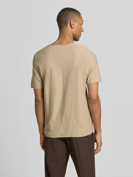 Männermodel trägt Regular Fit T-Shirt mit V-Ausschnitt von MCNEAL aus Reine Baumwolle, Rollsaum, beige, Rückenlänge 70 cm, Ganzkörperansicht Rückansicht.