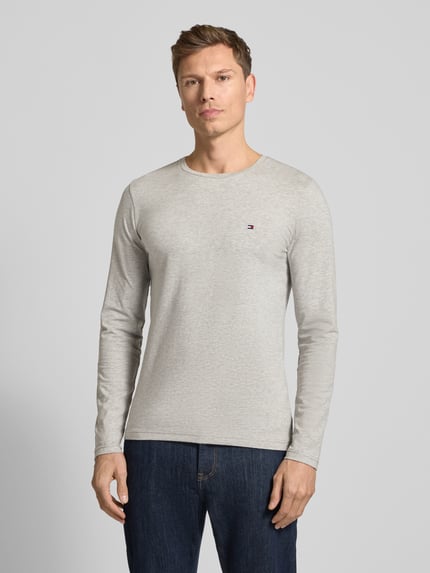 Männermodel trägt Slim Fit T-Shirt aus Baumwoll-Mix von Tommy Hilfiger, Optik: Unifarben, Label-Stitching-Applikation, Rundhals, Langarm, Materialverarbeitung: Jersey, Ganzkörperansicht von vorne.