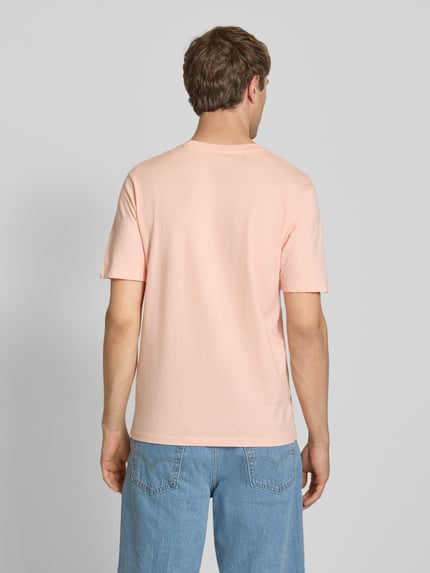 Mężczyzna model nosi T-Shirt mit Label-Print od Jack & Jones w kolorze jasnoróżowym, bawełna, krój regular fit, widok całej sylwetki od tyłu.