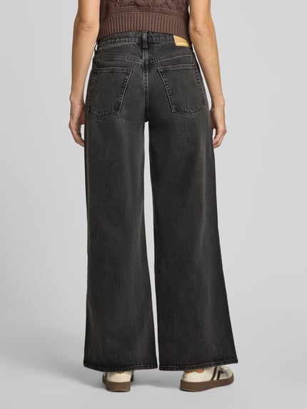 Frauenmodel trägt Wide & Loose Fit Jeans aus reiner Baumwolle Modell 'ASTRAEAAS' von ARMEDANGELS in Dunkelgrau mit breitem Bein, Ganzkörperansicht Rückansicht, Damen Wide & Loose Fit Jeans von ARMEDANGELS.