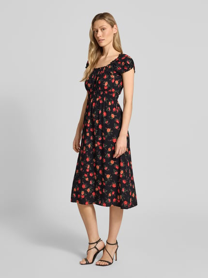Frauenmodel trägt Midikleid aus Viskose mit Karree-Ausschnitt von Apricot, schwarz mit rotem Blumenmuster, taillierte Passform, Puffärmel, Ganzkörperansicht von vorne.