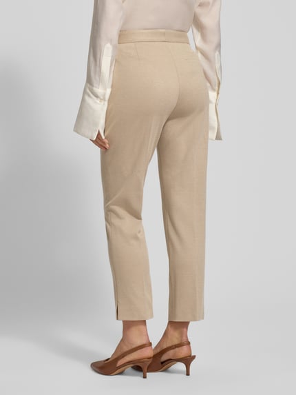 Modelka kobieca nosi Regular Fit schmale Hose aus Viskose-Mix Model 'Tapria-Crop4' od BOSS w beżowym kolorze z drobnym wzorem, długość do kostek, imitacja kieszeni, boczne kieszenie, rozporek na guziki i schiebehaken, boczne rozcięcia nogawek, widok całej sylwetki z tyłu.