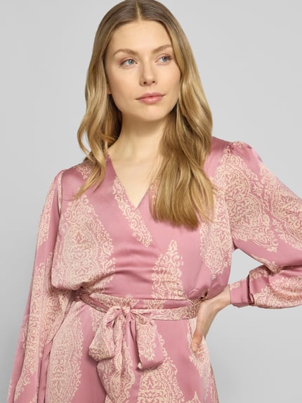 Vrouwenmodel draagt Regular fit avondjurk met all-over paisleyprint model 'Bretti' van Neo Noir in roze satijn, V-hals, getailleerd, afneembare stoffen band, wikkellook, met lange mouwen, ingelegde mouwboorden, Nahaufnahme bovenlichaam.