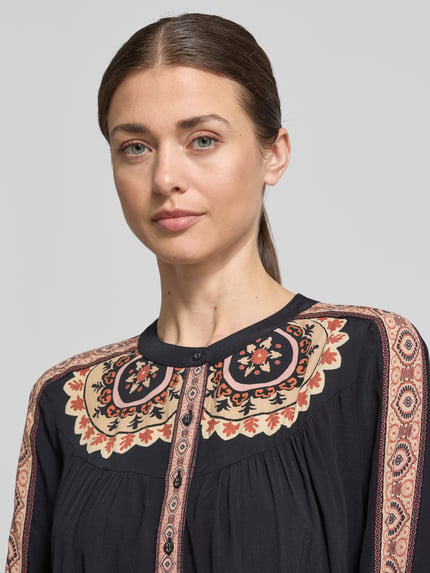 Frauenmodel trägt Relaxed Fit Bluse mit Rundhalsausschnitt Modell 'VALDA' von Bash aus reiner Viskose im Allover-Look, Nahaufnahme Oberkörper.