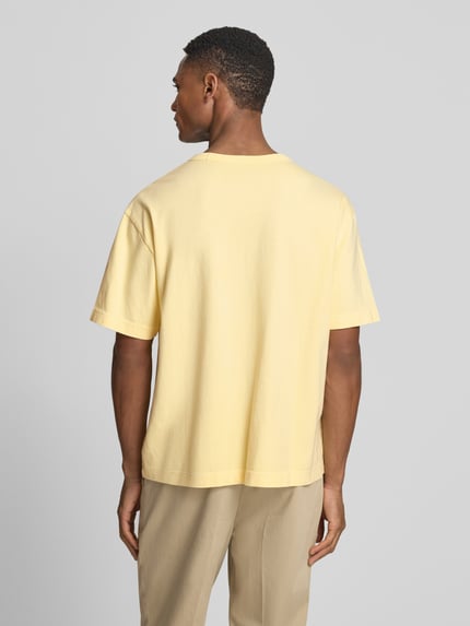 Männermodel trägt Cropped T-Shirt mit Rundhalsausschnitt von GAP in Hellgelb, reine Baumwolle, lockere Passform, Ganzkörperansicht Rückansicht.