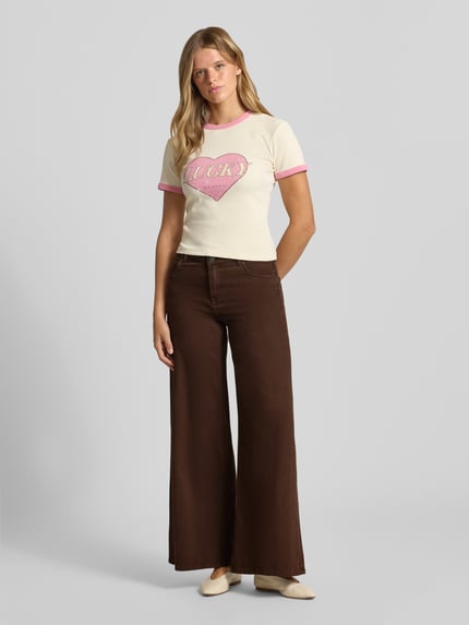 Frauenmodel trägt Wide Fit Jeans mit Eingrifftaschen von REVIEW aus reiner Baumwolle in Dunkelbraun, Ganzkörperansicht von vorne.
