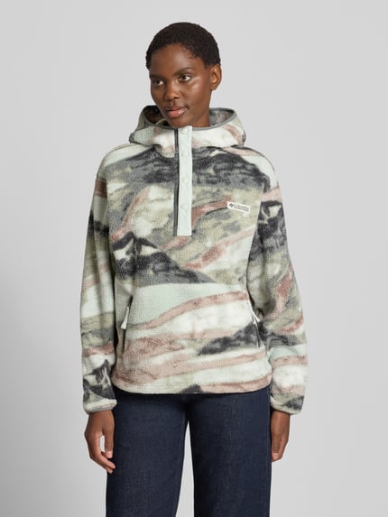 Vrouwenmodel draagt Hoodie met Label-Patch model 'Helvetia' van Columbia, fleece, straight fit, kap, korte drukknoopsluiting, zijritszakken, meerkleurige tinten in beige, grijs en groen, zachte textuur, voorkant geheel zichtbaar, Ganzkörperaanzicht van voren.