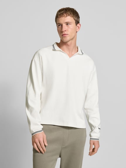 Männermodel trägt Strickpolo aus puur katoen Modell 'JORNIAGARA' von JACK & JONES met V-hals, contrasterende platte kraag, labeldetail, los model, crèmekleurig, Ganzkörperansicht van voren.