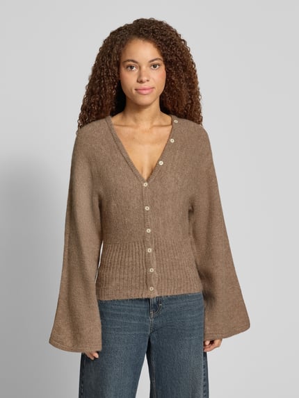Vrouwenmodel draagt Regular Fit gebreid jack met wol, Gina Tricot, elastische materiaalmix, ribboorden, knoopsluiting, met lange mouwen, ruglengte in maat S 53 cm, mouwlengte 49 cm, effen bruin, geribde textuur, volledige voorkant weergave.