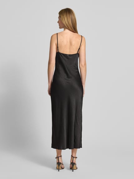 Frauenmodel trägt Midikleid mit Ziersteinbesatz Modell 'NEW AKILINA' von Guess in schwarzer Satin-Optik, körpernahe Passform, Spaghettiträger, Crinkle-Optik, Midilänge, Wasserfall-Ausschnitt, Ganzkörperansicht Rückansicht.