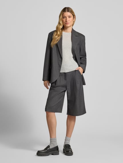Frauenmodel trägt Strickpullover mit 1/2-Arm und Rundhalsausschnitt von Christian Berg Woman aus reiner Baumwolle im Slim Fit, dezente helle Farbe, kombiniert mit dunklem Blazer und Shorts, Ganzkörperansicht von vorne.