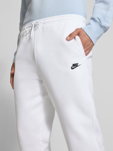 Männermodel trägt Sweatpants mit Label-Stitching und Gesäßtasche von Nike aus Baumwoll-Mix in Weiß, Regular-Fit, Nahaufnahme Oberkörper.