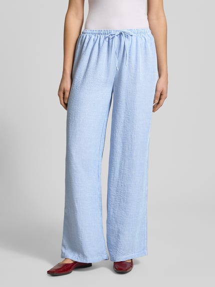 Frauenmodel trägt Pyjama Pants mit elastischem Bund von Review, Loose-Fit, blauer und weißer Streifenstoff, Ganzkörperansicht von vorne. Bundweite bei Größe S 41 cm, Innenbeinlänge 77 cm.