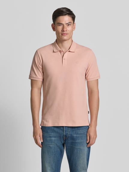 Męski model trägt Slim Fit Poloshirt mit Stitching von Jack & Jones Premium aus bawełna, krój slim fit, listwa guzikowa, długość tyłu w rozmiarze M: 70 cm, kolor jasnoróżowy, proste kształty, gładka tekstura, Ganzkörperansicht von vorne.