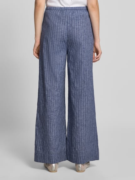 Frauenmodel trägt Wide Leg Hose mit Tunnelzug Modell 'HEIFA' von Neo Noir aus reiner Baumwolle, blau mit weißen Streifen, Ganzkörperansicht Rückansicht.
