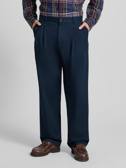 Männermodel trägt Wide Fit Bundfaltenhose aus reiner Baumwolle von Tommy Hilfiger, Optik: Unifarben, Ganzkörperansicht von vorne.