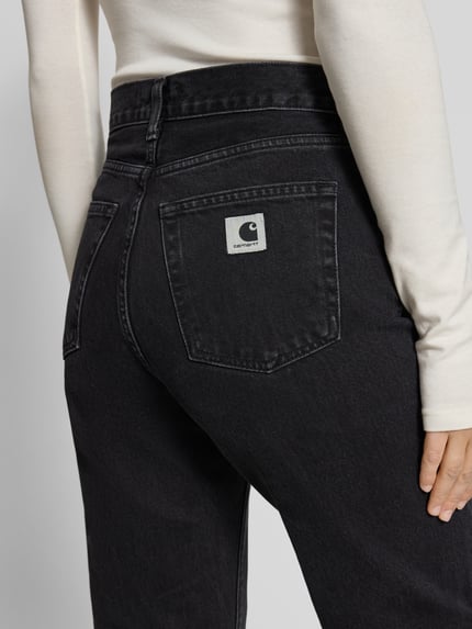 Frauenmodel trägt Jeans mit Eingrifftaschen Modell 'Noxon' von Carhartt Work In Progress aus reiner Baumwolle im Relaxed-Fit, Dunkelblau mit sichtbarer Gesäßtasche, Detailaufnahme Rückenansicht.