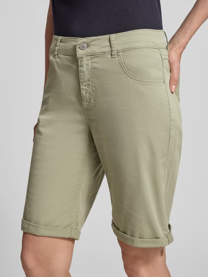 Vrouwenmodel draagt Bermudas met omslag en steekzakken van Angels in lichtgroen, regular fit, knoop- en ritssluiting, bandwijdte maat 36: 40 cm, binnenbeenlengte maat 36: 25 cm, detailopname heup en bovenbenen.