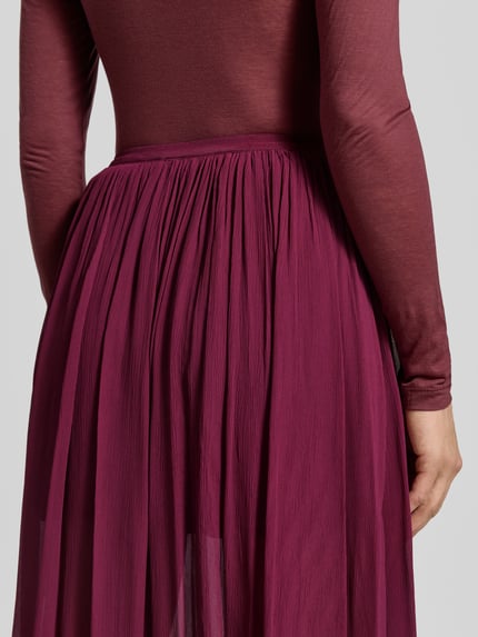 Frauenmodel trägt Maxirock aus reiner Viskose von Anine Bing, elastischer Bund, gerade Passform, glänzende Textur, Detailaufnahme Oberkörper.