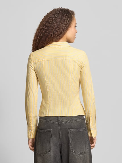 Vrouwenmodel draagt 'Fitted Hemdbluse mit Hemdblusenkragen' van Review in geel met witte strepen, elastische katoenmix, fitted fit, sportmanchetten, ruglengte 51 cm, mouwlengte 62 cm, langemouws, doorlopende knoopsluiting, achterkant, volledige lichaamsweergave.
