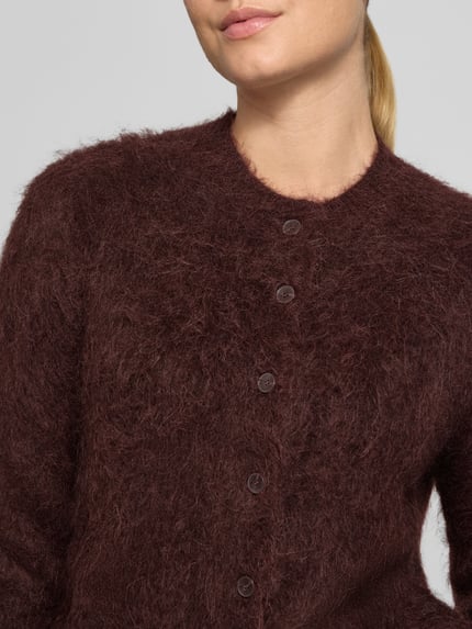 Frauenmodel trägt Strickjacke aus Alpaka-Mix Modell 'Tulinda' von someday, dunkelbraun, weiche flauschige Textur, Nahaufnahme Oberkörper. Damen Strickjacke aus Alpaka-Mix mit Stretch-Anteil, Regular Fit, Rundhalsausschnitt, Knopfleiste, Rückenlänge bei Größe 36: 53 cm, Ärmellänge bei Größe 36: 80 cm.