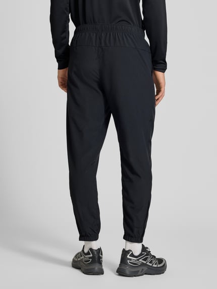 Männermodel trägt Form Pants mit Logo-Print und Eingrifftaschen von NIKE TRAINING in Schwarz, elastischer Bund, Abschlüsse, Ganzkörperansicht Rückansicht.