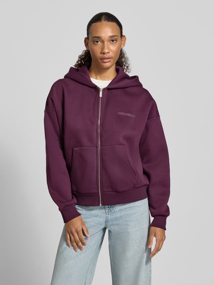 Vrouwenmodel draagt Relaxed Fit sweatjack uit katoenmix met labeldetail van REVIEW, diepe paarse kleur, kangoeroezak, capuchon, elastische boorden, geheel van voren bekeken, dames sweatjack, katoenmix, relaxed fit, labeldetail, gescheiden kangoeroezak, elastische boorden, capuchon. Ganzkörperansicht von vorne.
