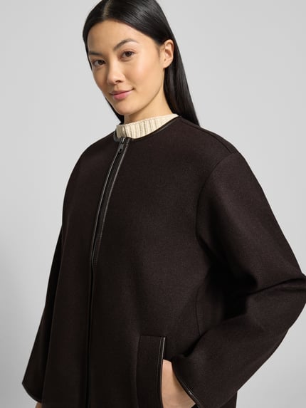 Frauenmodel trägt Oversized Mantel mit Schalkragen Modell 'FORTUNE MANJA' von Vero Moda in Melange-Optik mit Kontraststreifen, Filz, Nahaufnahme Oberkörper.