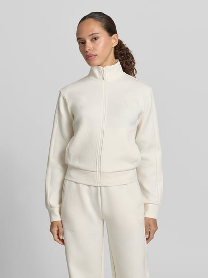 Frauenmodel trägt Sweatjacke mit Logo-Muster Modell 'CALISTA' von Guess Activewear in Creme, Material-Mix, Reißverschluss, Ganzkörperansicht von vorne.