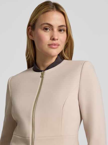 Frauenmodel trägt Kurzblazer mit Label-Detail von Rinascimento, taillierte Passform, Rundhalsausschnitt, Reißverschluss, Nahaufnahme Oberkörper.