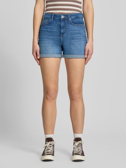 Vrouwenmodel draagt Regular Fit Jeansshorts uit katoenmix model 'JOSEPHINE' van Only in denimlook met labelpatch, 5-pocketmodel, knoop- en ritssluiting, riemlussen, katoenmix. Volledige lichaamsaanzicht van voren.
