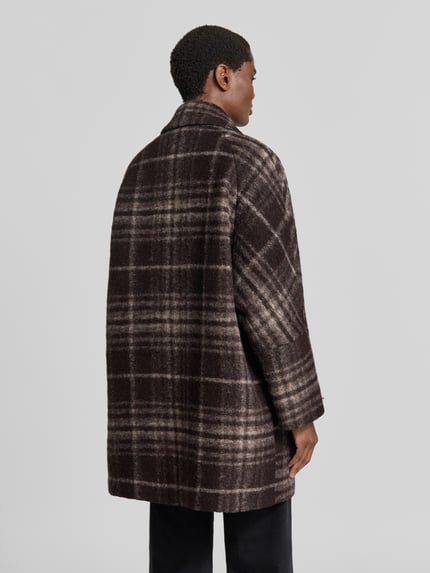 Frauenmodel trägt Relaxed Fit Mantel aus Woll-Mix von FUCHS SCHMITT, dunkle Karomuster, grobe Textur, Rückenansicht, Ganzkörperansicht Rückansicht. Damen Mantel, Umlegekragen, Eingrifftaschen, Knopfleiste, Rückenlänge 79 cm, Schulterbreite 42 cm, Brustweite 68 cm, Ärmellänge 62 cm.