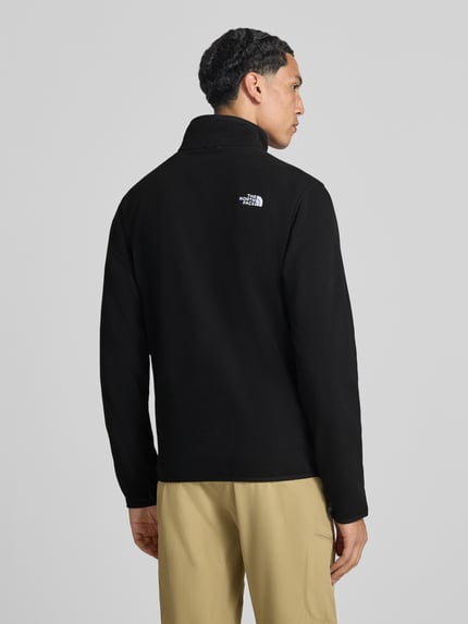 Männermodel trägt schwarze Fleecejacke mit Reißverschluss Modell 'GLACI' von The North Face, tailliert, Rückansicht, Ganzkörperansicht.