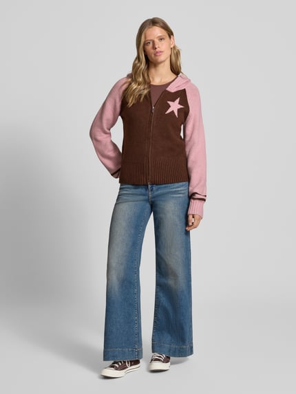 Frauenmodel trägt Strickjacke mit Zweiwege-Reißverschluss Modell 'NOUGAT' von DAISY STREET, braun-rosa mit Stern, Material-Mix, Kapuze, Regular Fit, kombiniert mit blauen Jeans, Ganzkörperansicht von vorne.