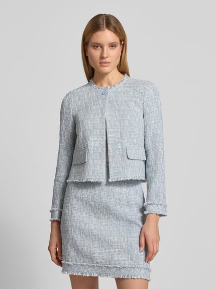 Frauenmodel trägt Regular Fit Blazer in Bouclé-Optik von Marc Cain aus Baumwoll-Mix mit Pattentaschen, Rundhalsausschnitt, Ganzkörperansicht von vorne.