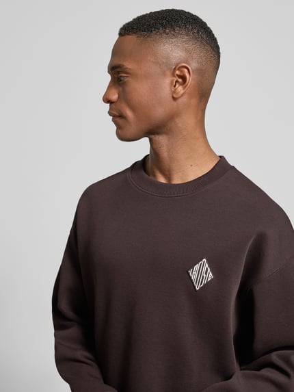 Männermodel trägt Loose Fit Sweatshirt aus Baumwoll-Mix von Lacoste, Optik: Unifarben, Logo-Stitching, Crew Neck, Nahaufnahme Oberkörper.