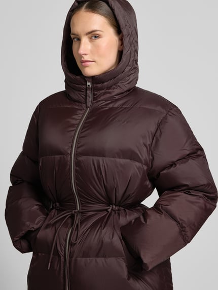 Frauenmodel trägt Jacke mit Kapuze und Zweiwege-Reißverschlus von Closed, prosty krój, kaptur, zamek błyskawiczny dwustronny, trok w talii, wpuszczane kieszenie, rękawy z dzianinowym wykończeniem, długość tyłu w rozmiarze S: 77 cm, szerokość ramion w rozmiarze S: 53 cm, szerokość w rozmiarze S: 62 cm, długość rękawów w rozmiarze S: 63 cm, ciemny brąz, błyszcząca faktura, Nahaufnahme górnej części ciała