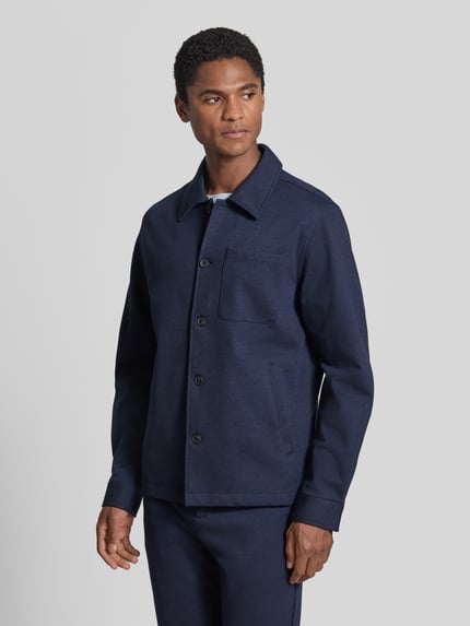Männermodel trägt Slim Fit Hemdjacke mit Viskose-Anteil von Lindbergh in Dunkelblau, aufgesetzte Taschen, Umlegekragen, Ganzkörperansicht von vorne.